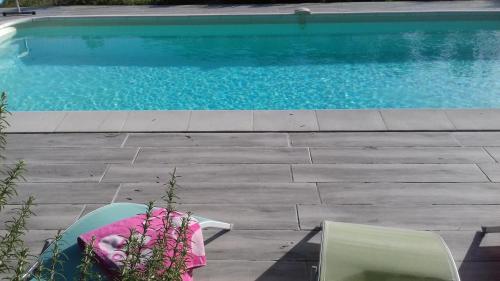 une piscine avec deux chaises à côté d'une table et d'une chaise dans l'établissement Bassegat nature, à Fox-Amphoux