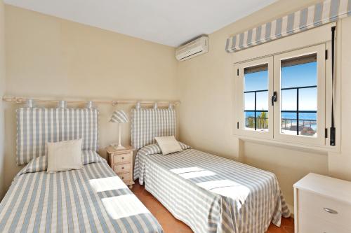 a bedroom with two beds and a window with the ocean at J96 Cabopino in Marbella