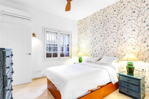 1 dormitorio con 1 cama blanca grande y papel pintado con motivos florales en A24 Cabopino, en Marbella