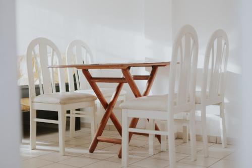 una mesa de madera y cuatro sillas blancas alrededor. en Leguizamon Flat - MZA Travel en Godoy Cruz