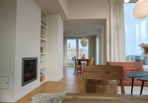 Una sala de estar con chimenea y una mesa. en Stijlvolle en lichtrijke design penthouse met prachtig uitzicht te Wenduine, en De Haan