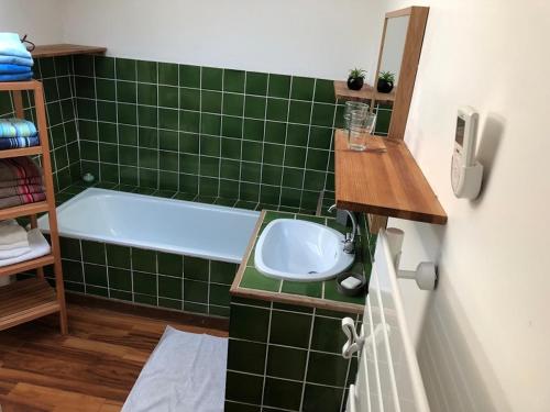 La salle de bains carrelée de couleur verte est pourvue d'un lavabo et d'une baignoire. dans l'établissement Le mas du castellanet, à Taradeau