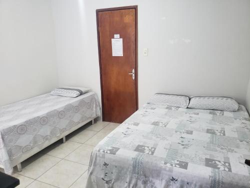 a bedroom with two beds and a wooden door at Hotel Ouro Preto in João Pessoa