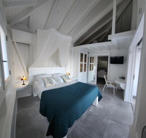 a white bedroom with a bed and a bathroom at La petite Villa in Terre-de-Haut