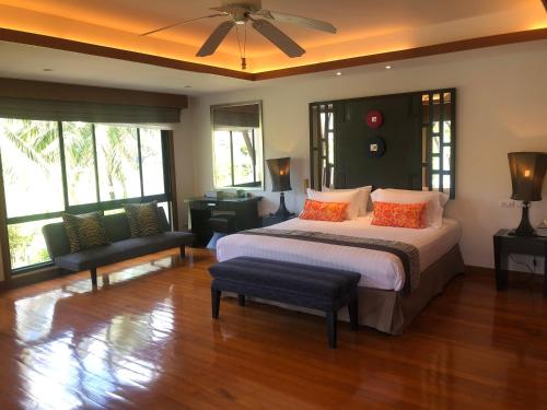 a bedroom with a bed and a chair and windows at Pool Villa Phuket 2 bedroom in Layan Beach