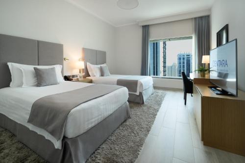 a hotel room with two beds and a flat screen tv at Centara West Bay Hotel & Residences Doha in Doha