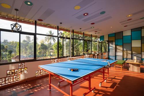 two ping pong tables in a room with windows at Zostel Coorg, Madikeri in Madikeri