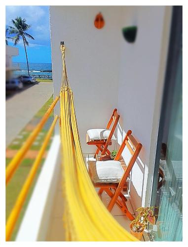 a hammock on a balcony with a view of the beach at Casa Arembepe in Camaçari