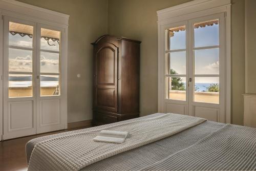 a bedroom with a bed and a cabinet and windows at Villa Comi in Mavráta