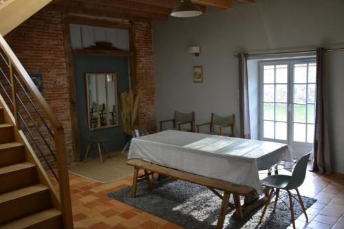 ein Wohnzimmer mit einem Tisch und einer Treppe in der Unterkunft Les écuries du château des Rieux in Saint-Martin-Terressus