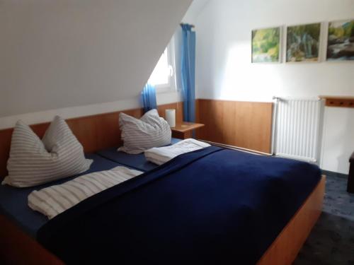 a bedroom with a blue bed with white pillows at Villa Tannerhof in Braunlage