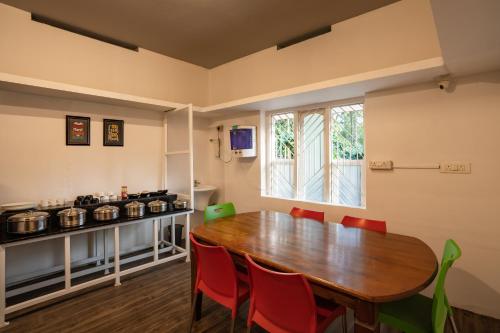 comedor con mesa de madera y sillas rojas en Zostel Coorg, Madikeri, en Madikeri