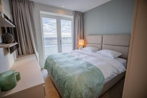 um quarto com uma cama grande e uma janela em Penthouse Royal, Luxurious and cozy with Sauna em Cadzand