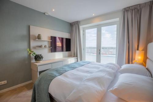 a bedroom with a large bed and a window at Penthouse Royal, Luxurious and cozy with Sauna in Cadzand