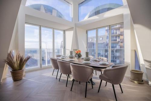a dining room with a table and chairs and large windows at Penthouse Royal, Luxurious and cozy with Sauna in Cadzand