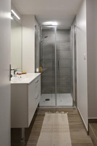 a white bathroom with a shower and a sink at Gîte du Gué Maraud in Magny-Lormes