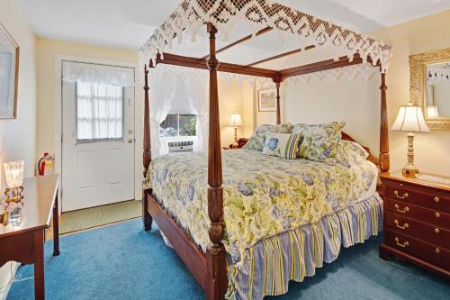 um quarto com uma cama de dossel e um tapete azul em The Lightkeeper’s Inn em Edgartown