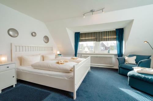 a bedroom with a white bed and a blue chair at Haushälfte Stranddiestel in Wenningstedt