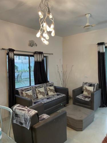 a living room with two couches and a chandelier at Samruddhi farms rooms S1 near mihan in Nagpur