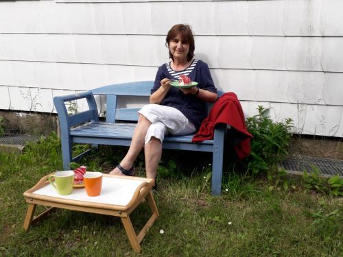 a woman sitting on a bench eating a plate of food at Villa Tannerhof in Braunlage