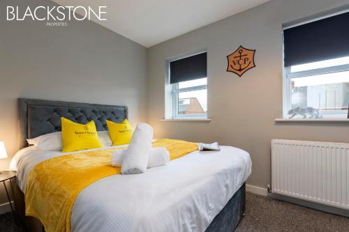 um quarto com uma cama grande com almofadas amarelas e brancas em Champagne House - 4 Bed Property plus 2 sofa beds by BPNE em Darlington