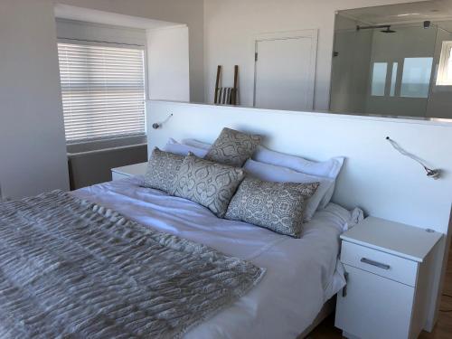 a bedroom with a large bed with pillows on it at Thyme & Tide Beach Villa in Yzerfontein