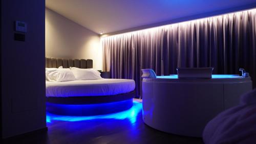Leoni Hotel & Private Spa - LOVE HOTEL في شيتا سانت أنجيلو: غرفة في الفندق مع سرير ومكتب مع أضواء زرقاء