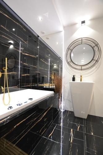 a bathroom with a tub and a large mirror at Apartament Gold in Złotoryja
