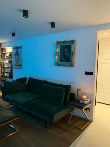 a living room with a green couch and a blue wall at Apartament Gold in Złotoryja