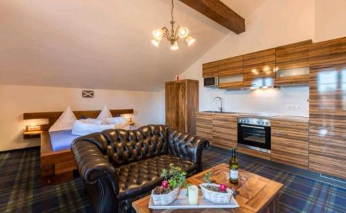 a living room with a leather couch and a bed at Ferienhaus Vitushöhle in Füssen