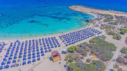 een luchtzicht op een strand met parasols en de oceaan bij Tsokkos Paradise Holiday Village in Ayia Napa