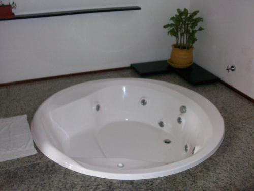 a white tub in a bathroom with a potted plant at Hotel Pousada Canoa Quebrada in Canoa Quebrada