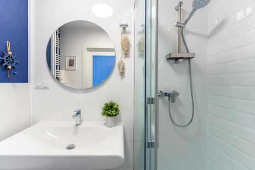 a bathroom with a sink and a shower with a mirror at Apartamenty Lighthouse Mrzeżyno in Mrzeżyno