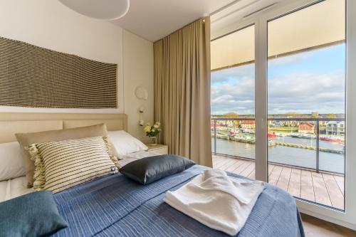 a bedroom with a bed and a large window at Apartamenty Lighthouse Mrzeżyno in Mrzeżyno