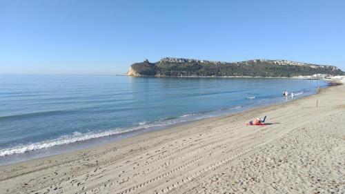 a person laying on a beach next to the ocean at Appartamento con vista mare a Terramala in Terra Mala