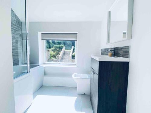 een witte badkamer met een toilet en een raam bij Exclusive 4-Bed House 10 minutes from Newcastle in Ravensworth