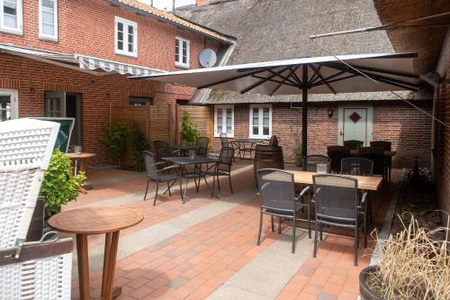 a patio with tables and chairs and an umbrella at Tetens Gasthof in Süderlügum