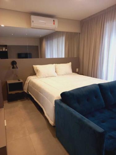 um quarto com uma cama grande e um sofá azul em Cityhome Platina Tatuapé em São Paulo