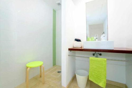 La salle de bains est pourvue d'un lavabo et d'un tabouret vert. dans l'établissement Casa Laila - acceso directo al mar, piscina y wifi, à Portopetro