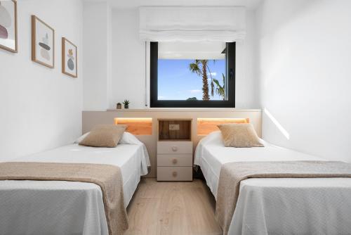 2 letti in una camera bianca con finestra di Garbí by enjoy Rocas Doradas a L'Ametlla de Mar