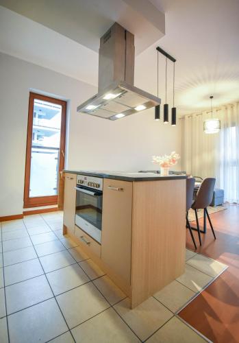 a kitchen with a stove top oven next to a table at Apartamenty Na Wyspie - Baltic Park - Apartamenty z sypialnią i parkingiem - ul Uzdrowiskowa 24-34 in Świnoujście