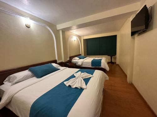 a bedroom with two beds with blue and white sheets at Hotel Donde Marcelo in Baños