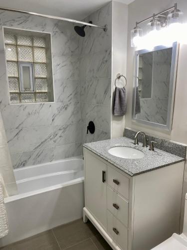 a white bathroom with a sink and a tub and a mirror at Lincoln Park Apartment with Backyard! in Chicago