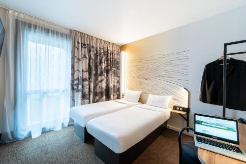 ヴィルヌーヴ・ダスクにあるB&B HOTEL Lille Grand Stadeのベッド2台とノートパソコンが備わるホテルルームです。