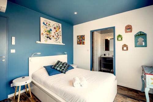 sypialnia z niebieskimi ścianami i białym łóżkiem w obiekcie La COLOC w mieście Lacanau