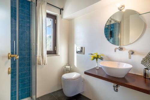a bathroom with a sink and a toilet and a mirror at Villa Tina in Taormina