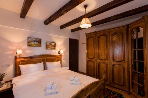 a bedroom with a large wooden bed with white sheets at Casa cu Cerdac in Nucşoara