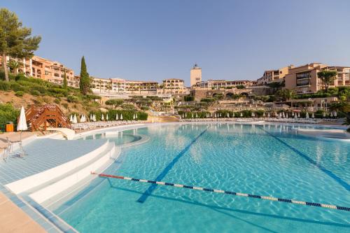 Village Pierre & Vacances Cap Esterel - Saint Raphaël Village في أغاي - سان رافائيل: مسبح كبير وبه مباني في الخلف