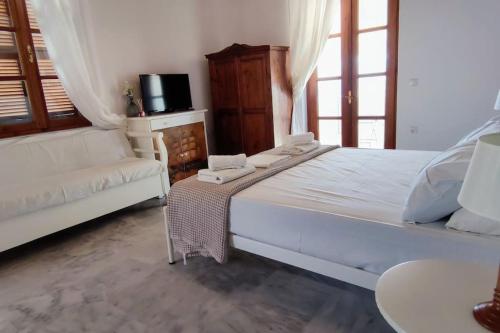 a bedroom with a large white bed and a couch at SUNSET STUDIO - HYDRA DREAM HOUSES in Hydra