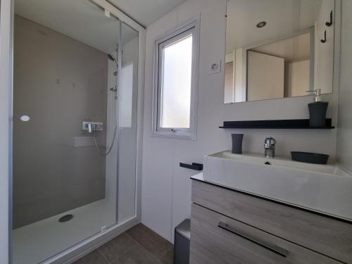 a bathroom with a shower and a sink and a mirror at Mobil home 2 chambres Camping **** (507) in Saint-Jean-de-Monts